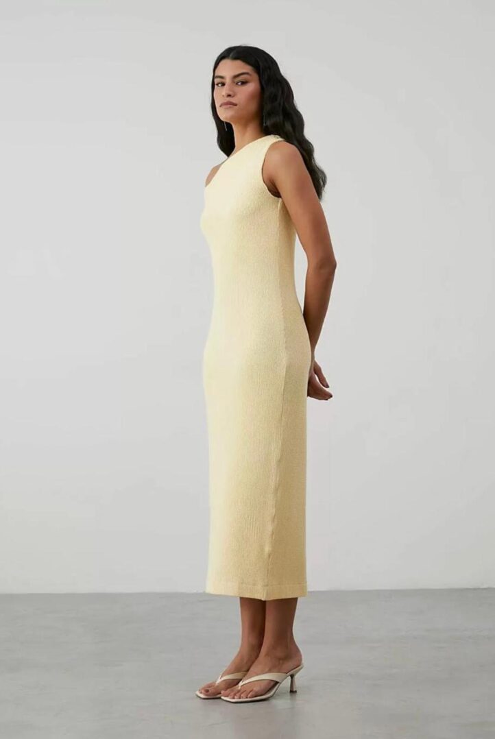 Woman in yellow dress, standing sideways.