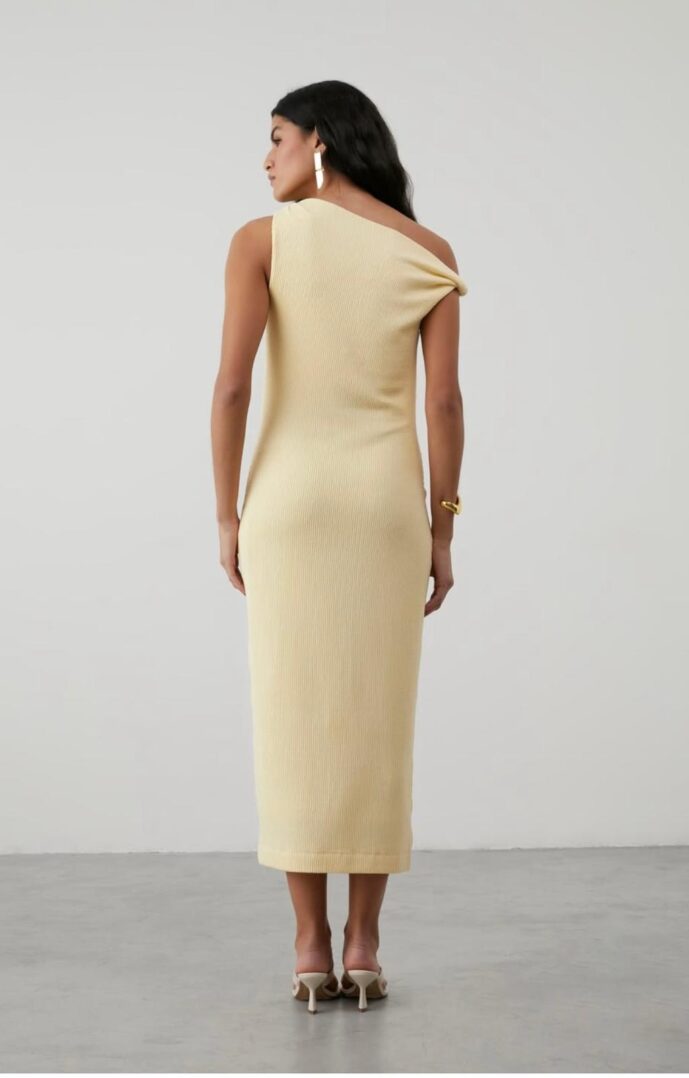 Woman in one-shoulder beige dress, back view.